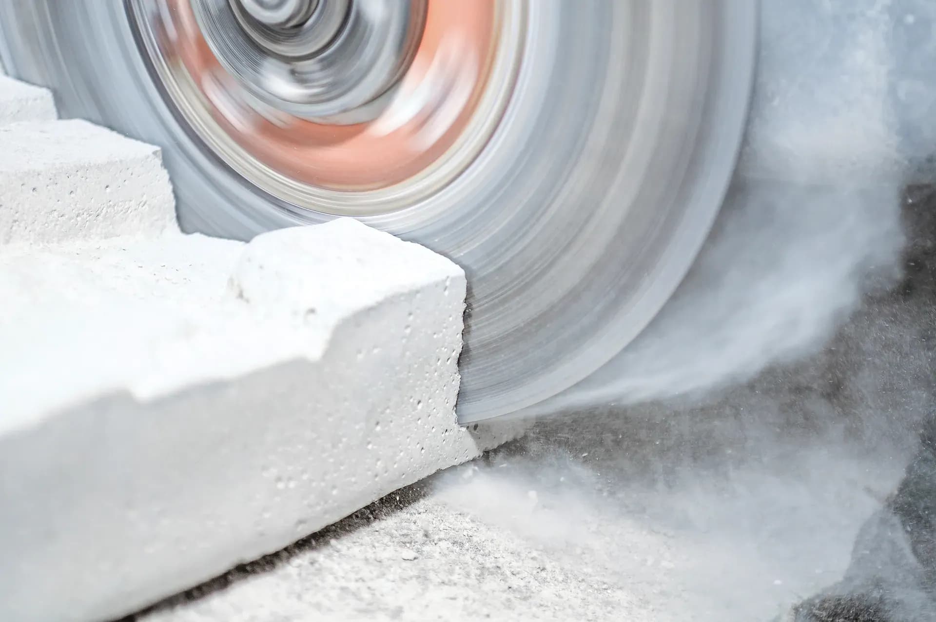 Scie tronçonneuse coupant un bloc de béton avec dégagement de poussière